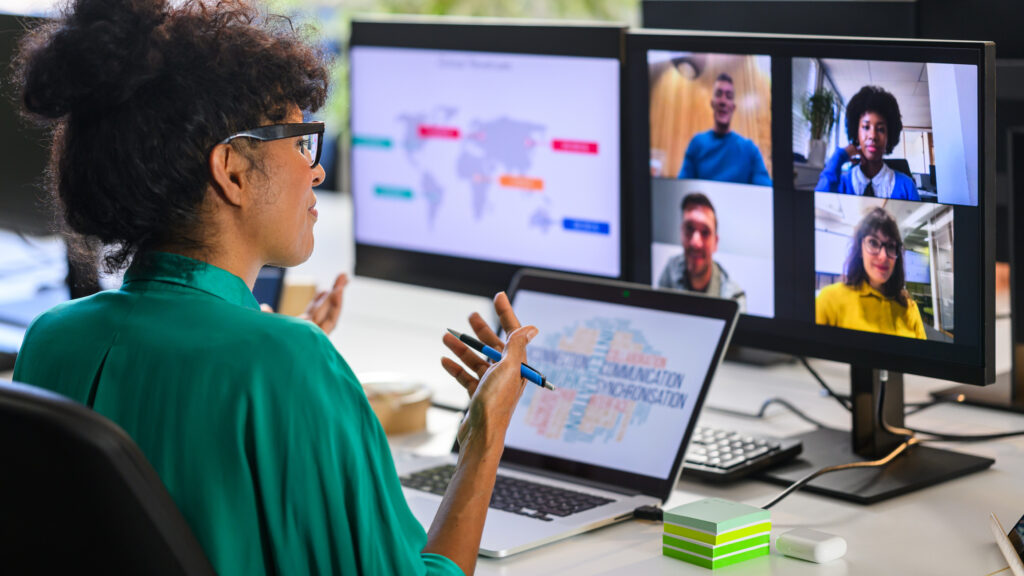 A woman interacting with a group online via computer screens.